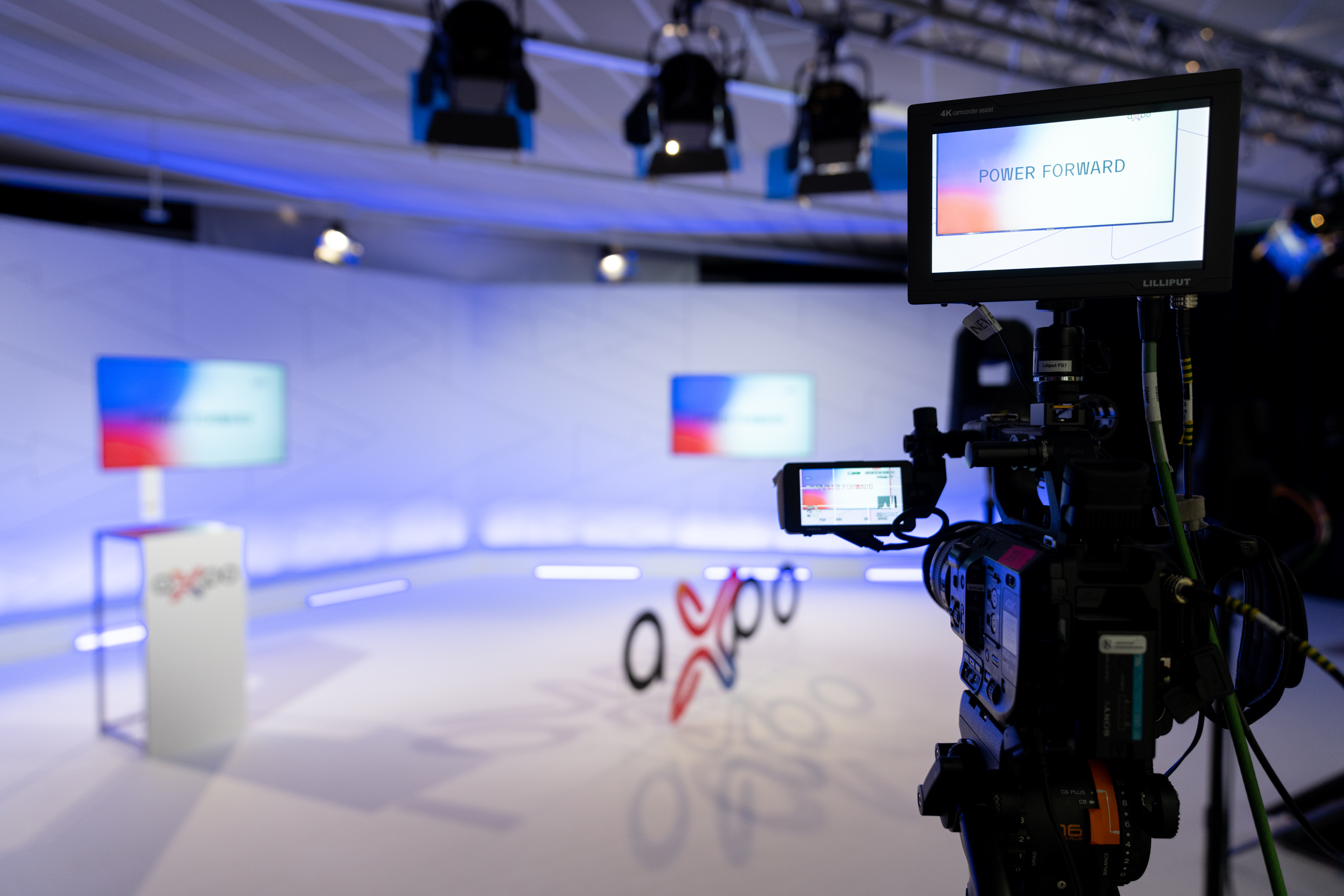 Im Vordergrund Kamera und im Hintergrund das Studio vom Axpo Rebranding Event mit Stehpult, Logo und Bildschirm